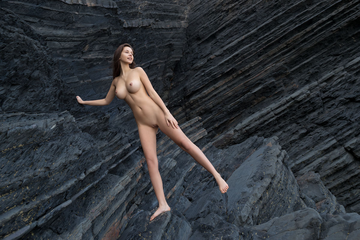 totally naked girl alisa i models up against a sea cliff during solo action