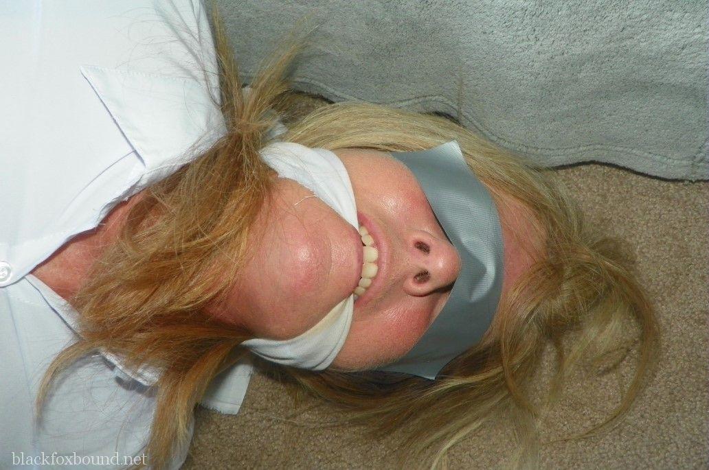 blonde woman is cleave gagged and hogtied in a white blouse and blue jeans