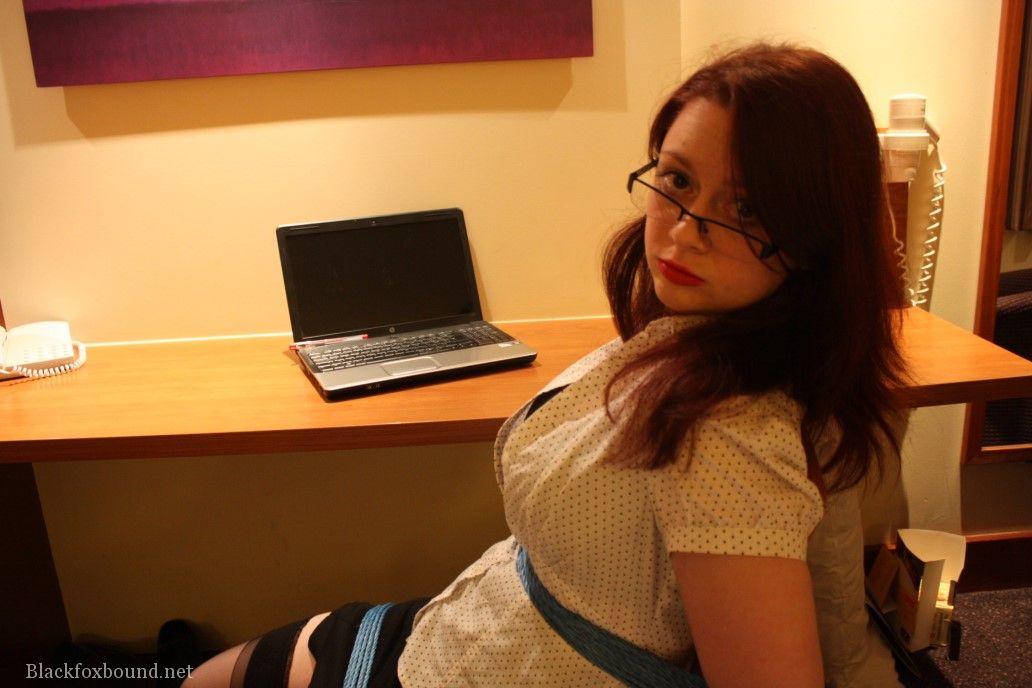 redhead secretary struggles against rope restraints while tied to a chair