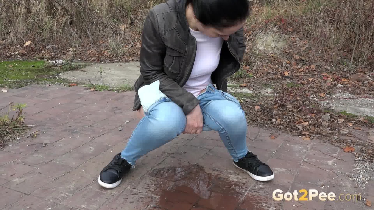 clothed woman corin pulls down her jeans for an urgent piss on a vacant lot