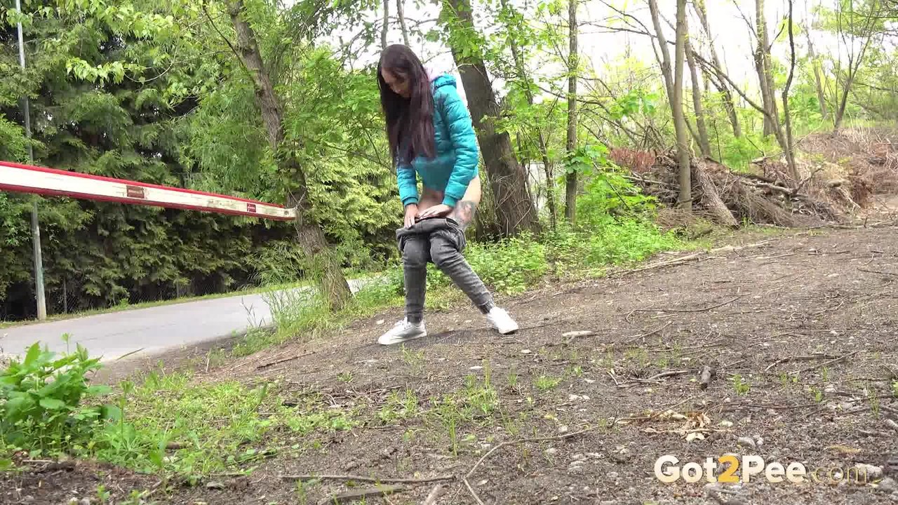 short taken girl squats to be on a path in the woods while wearing a coat