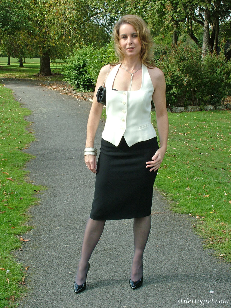 clothed lady takes a rest on a park bench in a long skirt, hose and stilettos