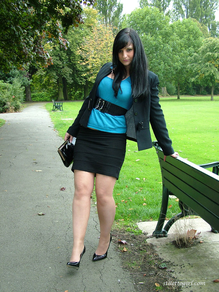 fully clothed female dangles her stiletto heels from hose clad feet on a bench
